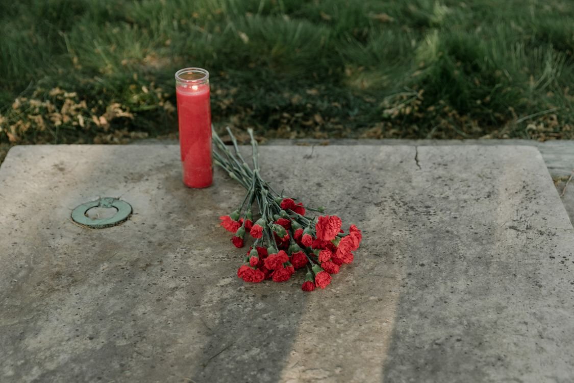 Illustrative memorial candle and flowers, not associated with the individuals named in this archive
